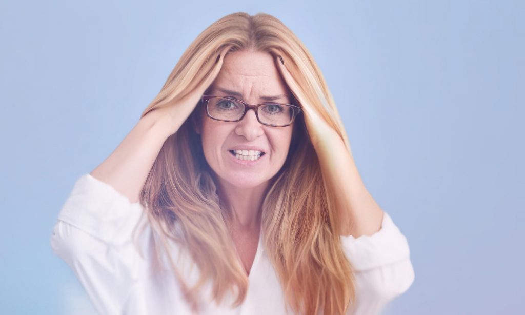 Женщина средних лет испытывает головную боль при мигрени
