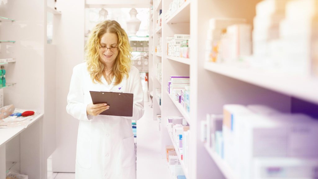 Фармацевт-женщина в аптеке ищет лекарство от головной боли